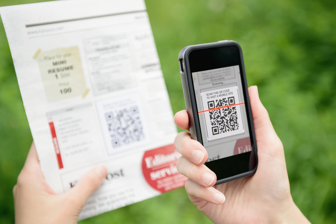 Eine Hand hält ein Handy, mit dem ein QR-Code gescannt wird.