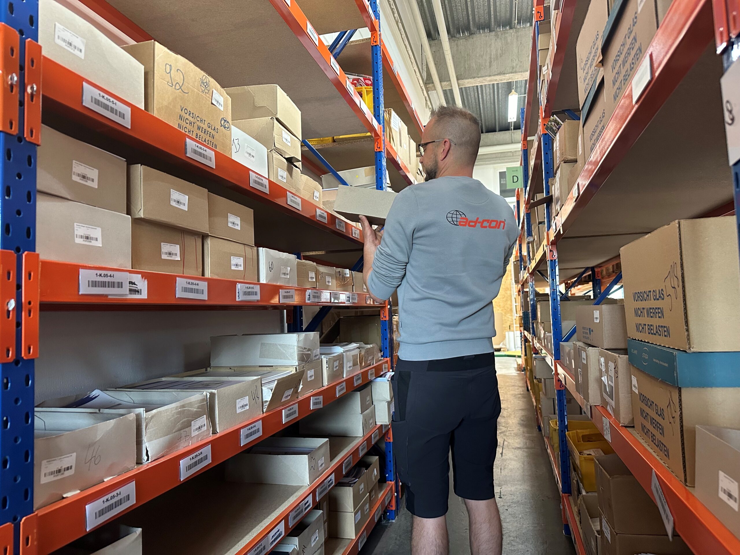 Fulfillment Lager bei ad-con GmbH. Ein Mitarbeitr pickt die Artikel.
